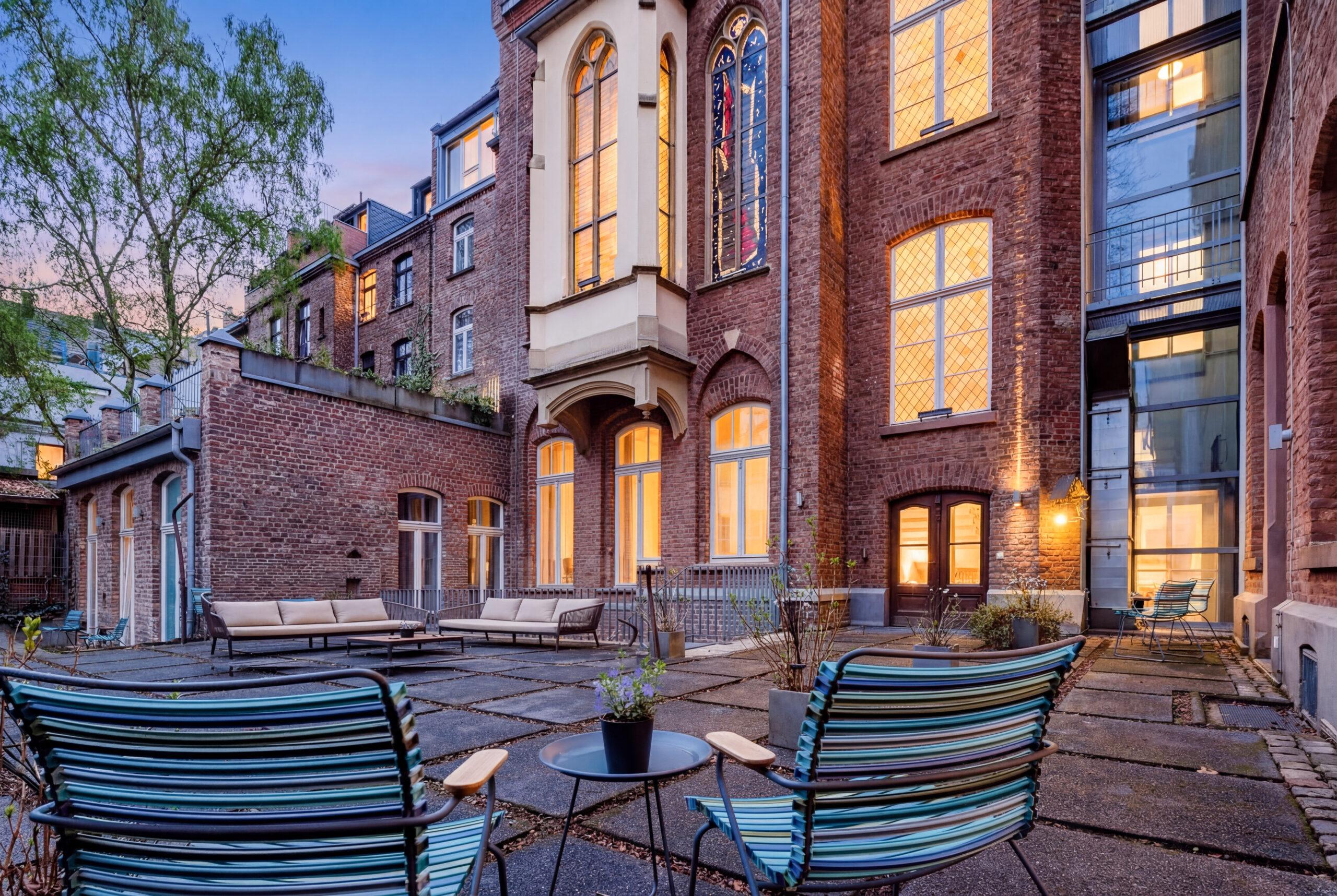 Außenbereich mit Sitzgelegenheiten vor historischer Backsteinfassade im Innenhof.